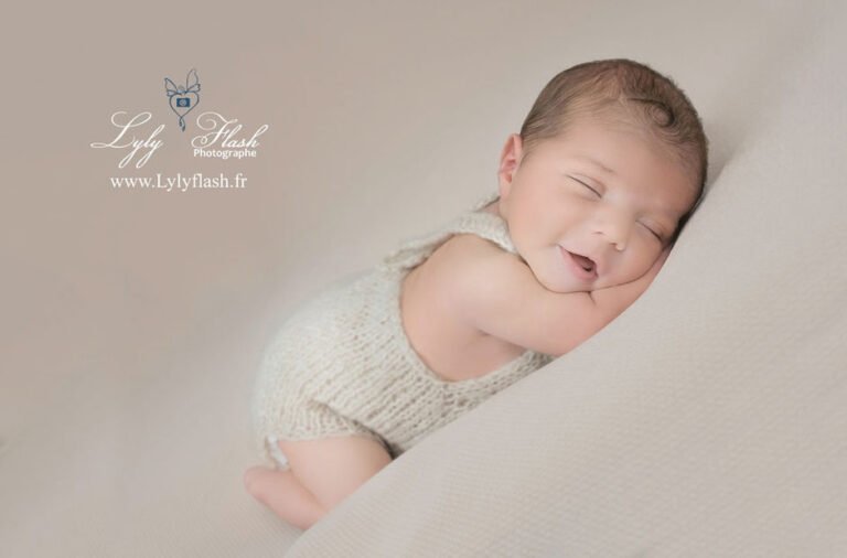photo bébé en shooting bebe naissance qui fait un grand sourire