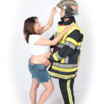 une femme enceinte met le casque a son mari pompier