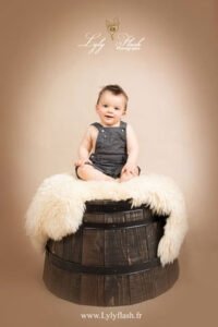 un bébé assis sur un grand tonneau au bois