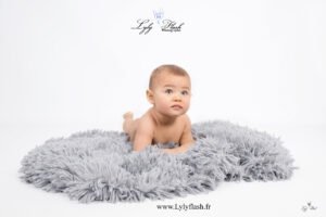 photo bébé sur tapis de poils gris le tout sur fond blanc lumineux pour ce bébé de 12 mois