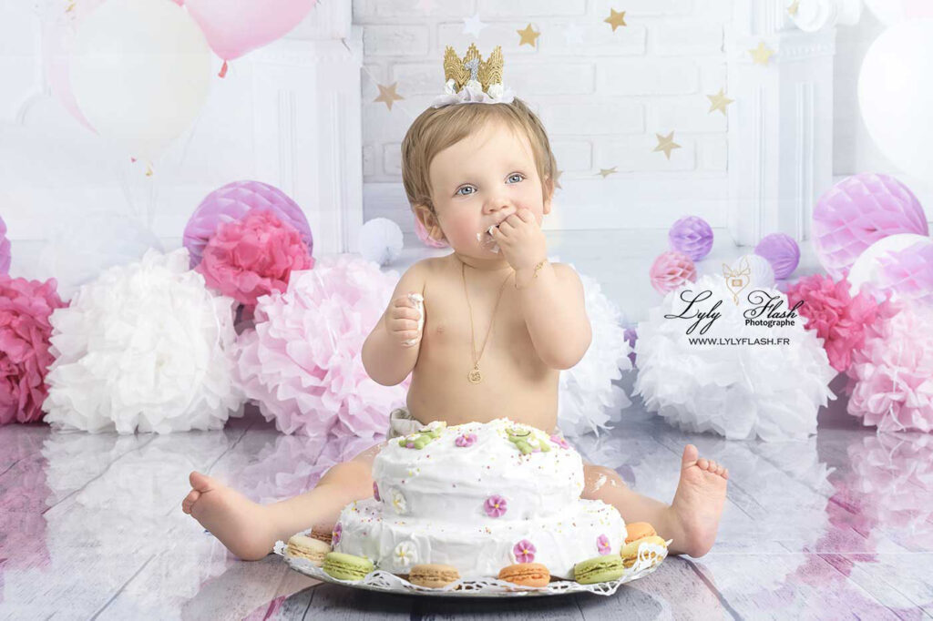 Photographe pour bébé à son anniversaire la petite fille mange son gâtau