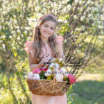 un portrait de petite fille en extérieur avec un beau panier de fleur et un soleil au zénith