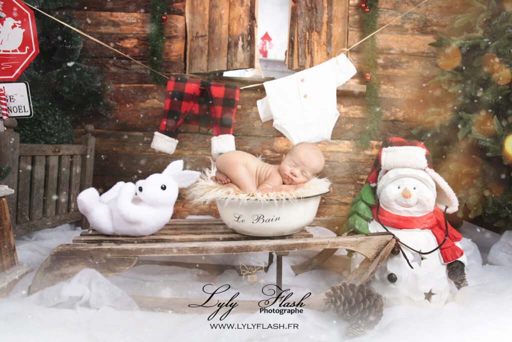 photo de naissance sur le thème de noël, un beau bébé pose en Tushy up pose, on voit ses vêtements sécher sur une corde a linge pendant qu'un lapin blanc fait des pirouette sur la neige