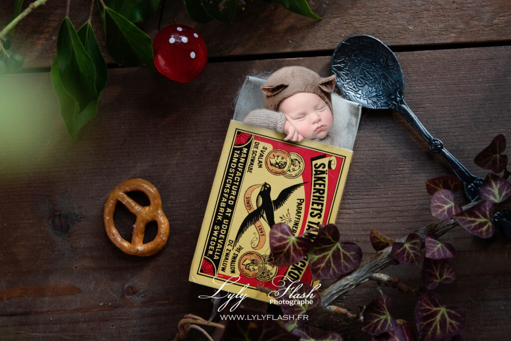 photo originale pour la naissance, un petit bébé déguisé en sourit avec ce beau chapeau en feutrine, dort dans une toute petite boite d'allumette, la photographie réalisée en macro photographie donne une dimension de tout petit pour mettre en valeur le bébé si petit de quelques jours après sa naissance. Quand la photographe utilise tout son art