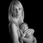 photographie en noir et blanc, d une splendide jeune maman blonde portant son bébé en peau contre peau. Séance photo naissance près de Bormes les Mimosas
