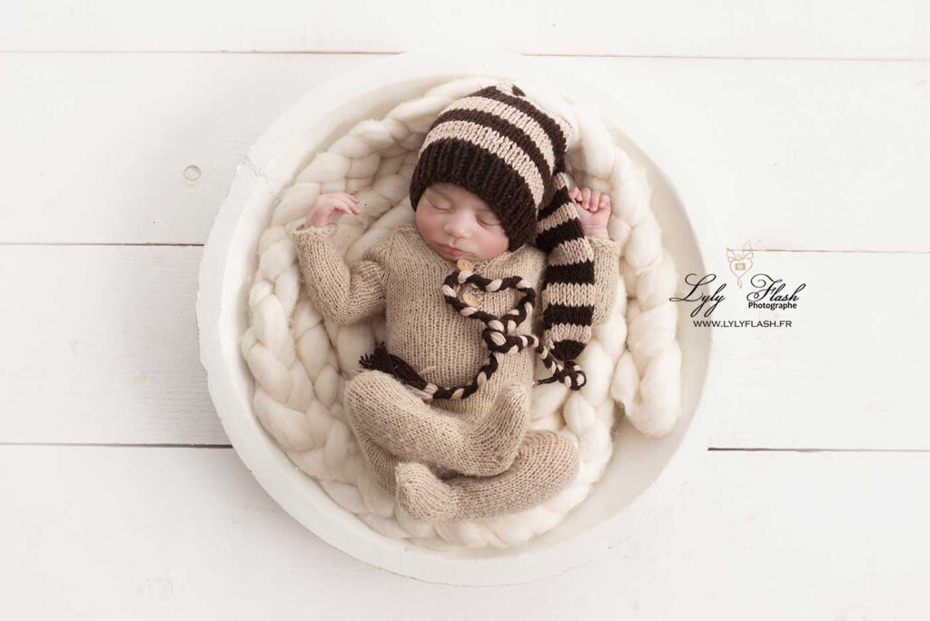 1 photo naissance cocoon le bébé dort dans un nid de laine avec un grand bonnet