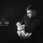 photographie noir et blanc d un jeune papa tenant pour la première fois son fils après la naissance