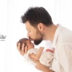 une photographie représentant un jeune papa embrassant le front de sa petite fille a la naissance, le tout baigné de lumière