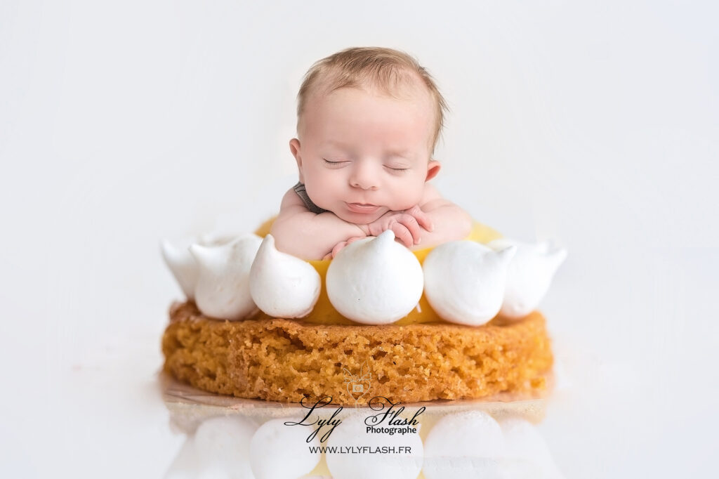 Photographe pour bébé a la naissance, un petit garçon de 2 semaines dort paisiblement une sur tartelette du pâtissier Lafitau à Brignoles. un moment de douceur et de gourmandise pour cette photographie poétique