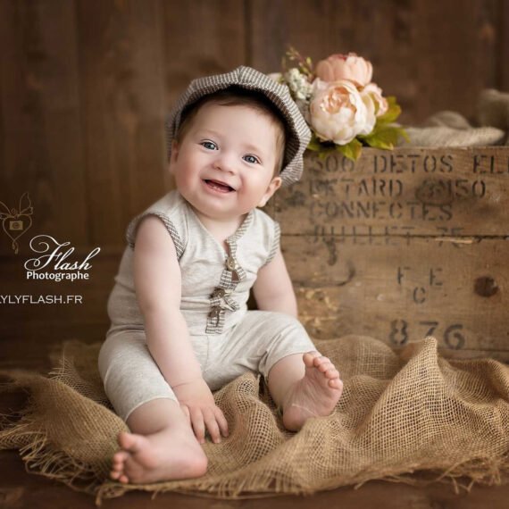 magnifique photo d un bébé de 12 mois en tenue vintage, ce petit garçon offre un sourire incroyable, une joie de vivre capturé par la photographe spécialisée dans le portrait du bébé depuis la naissance. avec un magnifique flou d arrière plan. Photographie réalisée près de Bormes-les-Mimosas