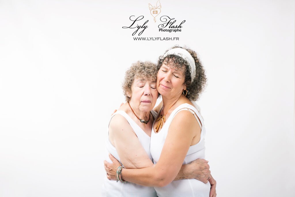 La grand-mère et sa petite fille sont assises au centre d'un grand fauteuil en velours. Les trois filles et le fils sont debout derrière elles, se penchant affectueusement vers elles. Leurs sourires radieux traduisent une forte connexion familiale.
