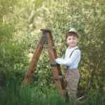 un beau petit garçon provençale monte sur une échelle en bois pour attraper le ciel, une photographie pleine de joie de vivre du monde de l'enfant