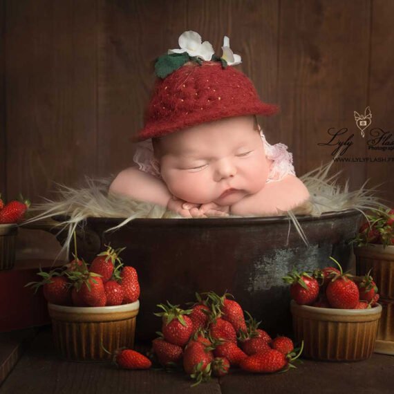 Photo artistique de nouveau-né sur une couverture texturée, posé sur le ventre, autour de Fraises du var réalisée dans le sud de la France.