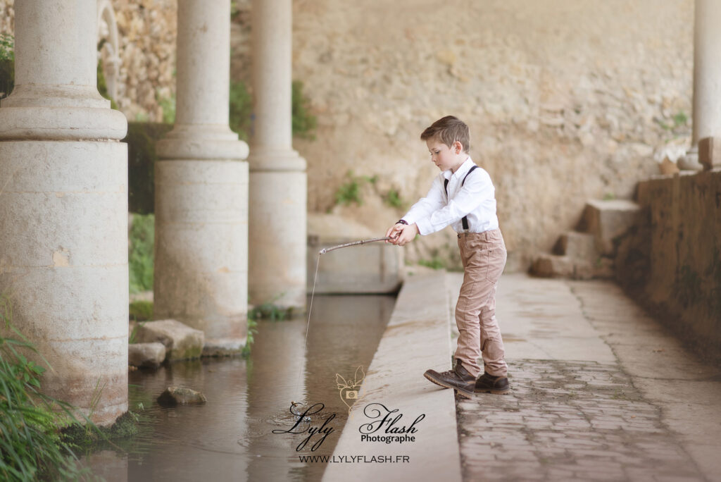 un jeune garçon en chemise joliment habillé joue a la pèche dans un lavoir de Provence, parce que le jeu et la découvert prend vie partout avec les enfants. Seul les limites du monde freine les enfants de demain