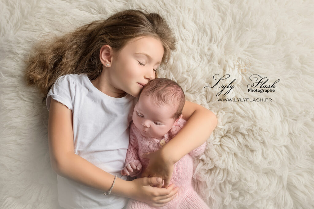 photographie d'une petite fille à la naissance avec sa grande sœur qui l'embrasse
