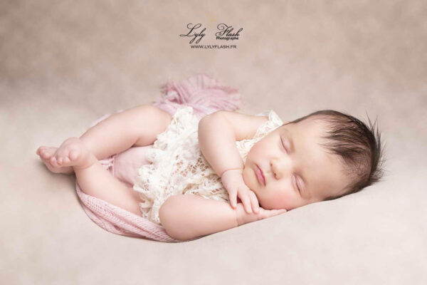une belle petite fille tout juste né dans un wrap en posing sur le côté pour sa séance photo naissance, le tout dans des tons doux et rose poudré, un magnifique souvenir familiale réalisé par la photographe lyly flash près de Le Luc en Provence